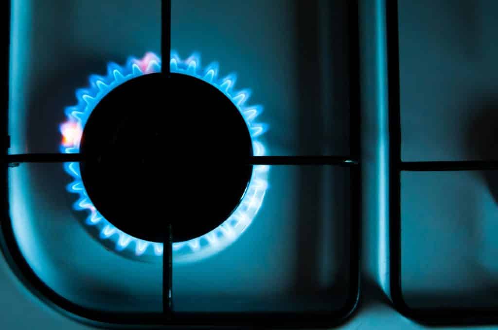 Close up photo of a gas hob on a domestic stove - a black central ring surrounded with a blue gas flame
